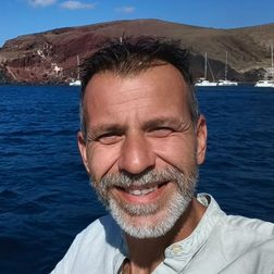 Chris, a Greece Holiday Tours guide, smiling by the sea near Red Beach