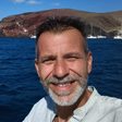 Chris, a Greece Holiday Tours guide, smiling by the sea near Red Beach