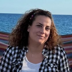 Chrysa, a Greece Holiday Tours guide, smiling by the sea