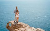 Couple embracing on the edge of a sea cliff above deep blue water