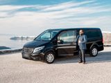 Black Mercedes van and its driver, parked on a gravel lot above the caldera