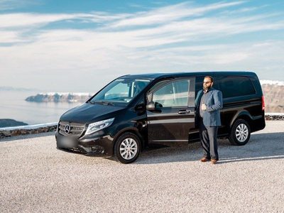 Black Mercedes van and its driver, parked on a gravel lot above the caldera
