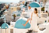 Couple playing for the camera on a rooftop by the blue domes of Oia