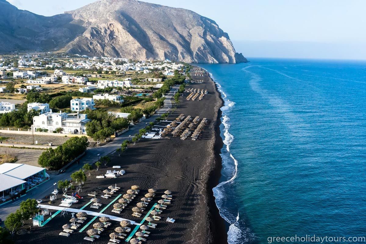 Sunbeds and umbrellas on the black sand of Perivolos beach, Santorini
