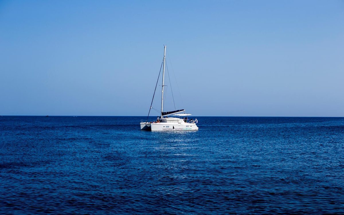 White sailing catamaran at anchor on calm open sea