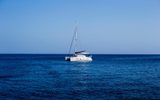 White sailing catamaran at anchor on calm open sea
