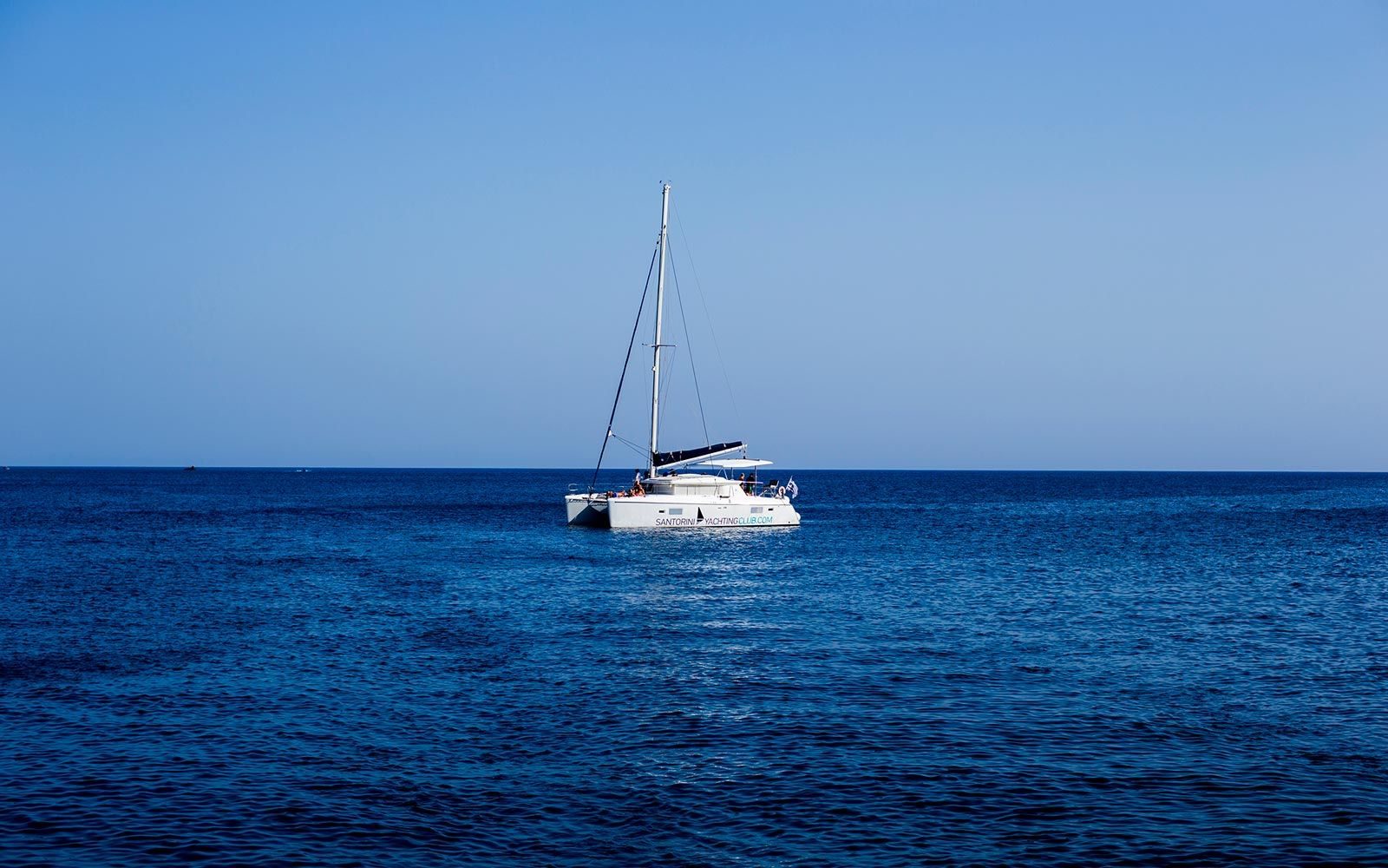 White sailing catamaran at anchor on calm open sea