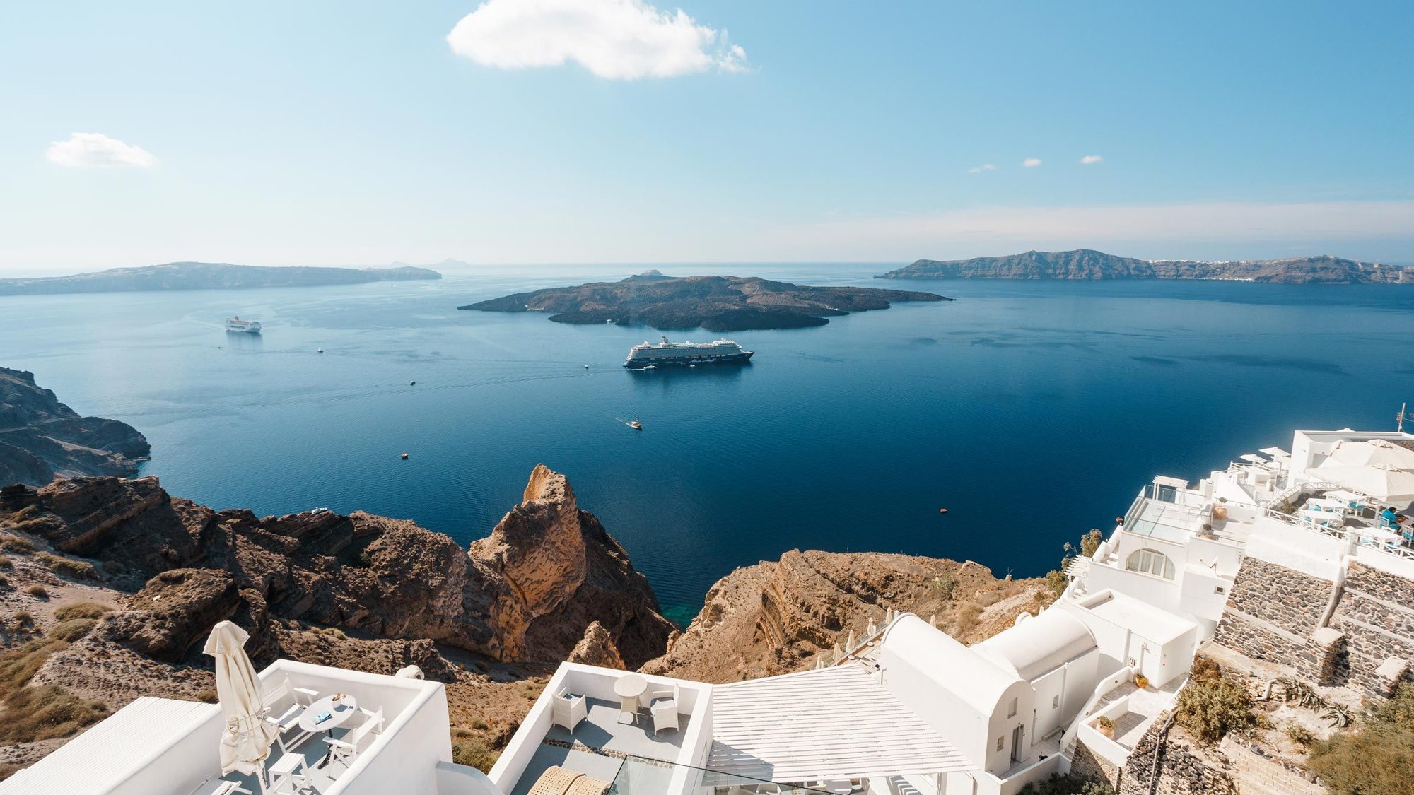Cruise ship in the Santorini caldera near the volcano, seen over whitewashed cliffside terraces