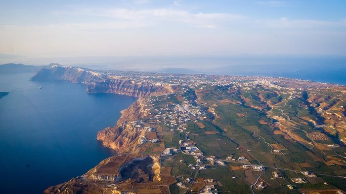 Aerial view of Santorini's caldera cliffs, villages and vineyards from a helicopter