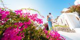Couple in a blue dress and white shirt embracing behind pink bougainvillea