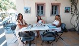 Three women at a marble table with tasting glasses of wine on a winery terrace