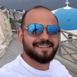 Vasilis, a Greece Holiday Tours guide, in front of a blue-domed church